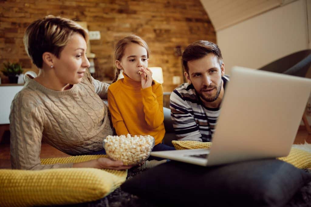 Family watching a limited series together at home with popcorn